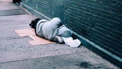 Homeless person lying on cardboard on the floor