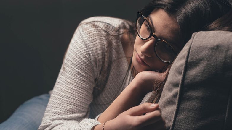 Pensive woman lying on sofa