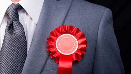 Politician wearing red rosette