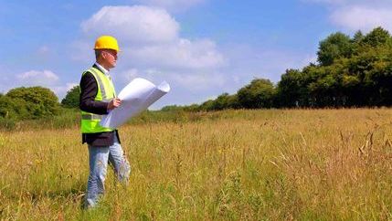 Builder in field with development plans